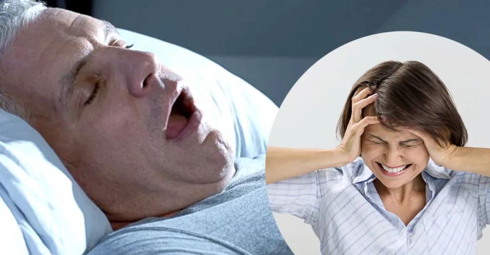 Couple in bed: man snoring with mouth open while wife covers her ears