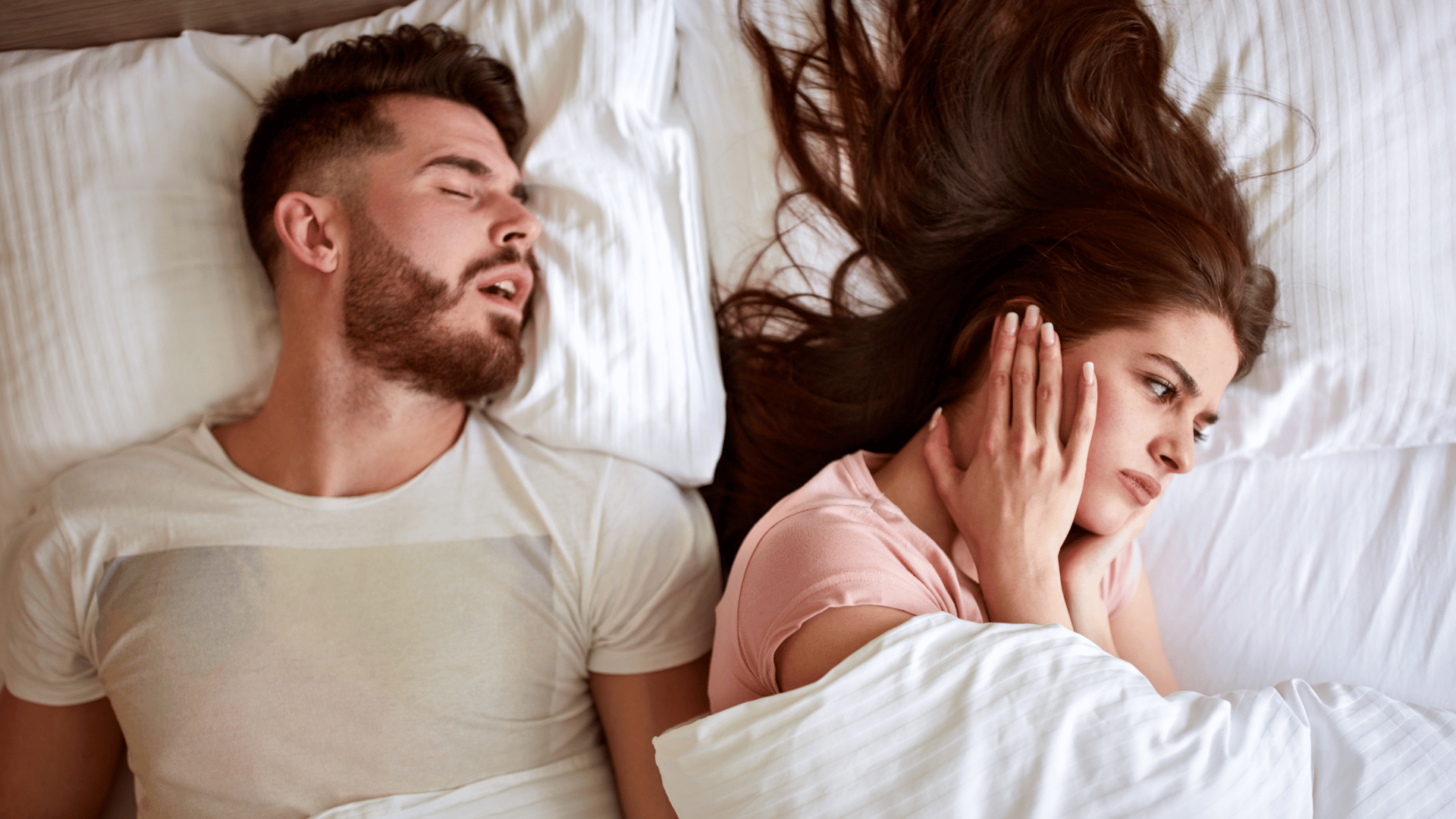 Woman covering her ears while her partner snores loudly